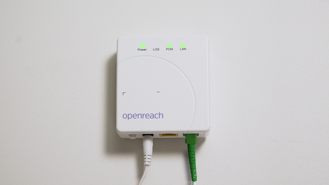 ONT Openreach modem - a small white box with LEDs on a wall. Two cables are attached to the bottom. ONT Openreach modem - a small white box with LEDs on a wall. Two cables are attached to the bottom.